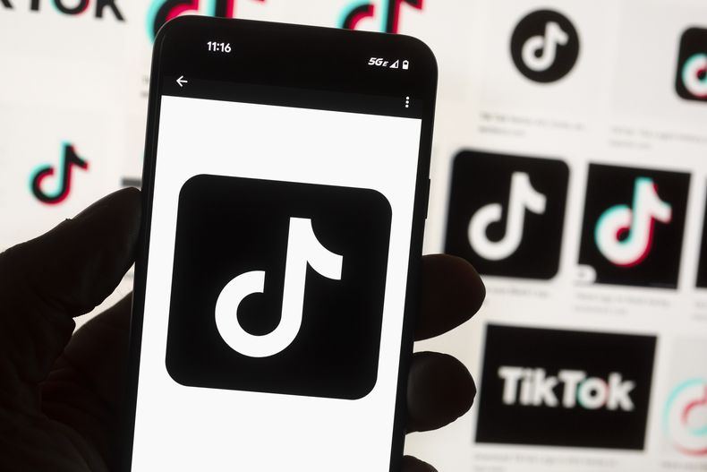 ARCHIVO - El logotipo de TikTok aparece en un celular frente a una pantalla de computadora que muestra la pantalla de inicio de TikTok, el 14 de octubre de 2022, en Boston. (AP Foto/Michael Dwyer, Archivo)