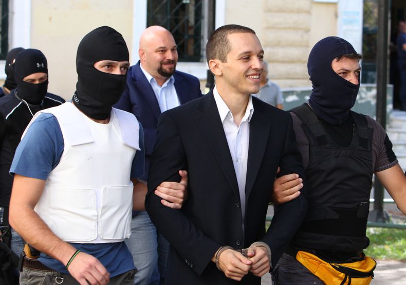 Ilias Kasidiaris (centro), legislador del partido griego Amanecer Dorado, de extrema derecha, es escoltado por dos agentes antiterroristas hacia un tribunal para una audiencia preliminar sobre los cargos de participar en una organizaci&oacute;n criminal,