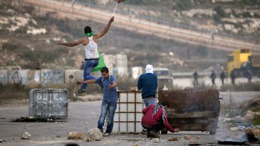 americateve | Un manifestante palestino sostiene una bandera palestina mientras salta durante enfrentamientos con soldados israel&iacute;es fuera de la prisi&oacute;n militar de Ofer, cerca de la ciudad cisjordana de Ramala, el 11 de noviembre de 2014. (Foto AP/Majdi M