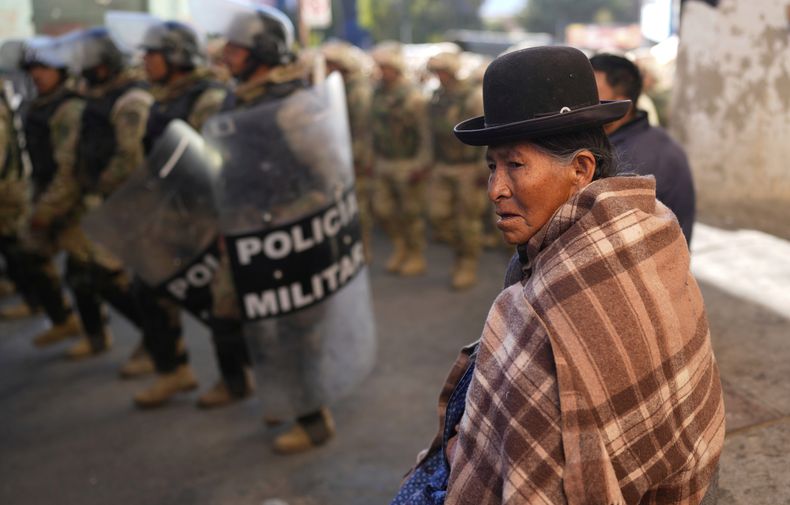 Una mujer observa a la policía militar de Bolivia patrullando luego de que fueran despejadas las rutas bloqueadas por simpatizantes del expresidente Evo Morales que reclaman que pueda ser candidato presidencial en las elecciones, en Llallagua, Bolivia, el viernes 13 de junio de 2025. (AP Foto/Juan Karita).