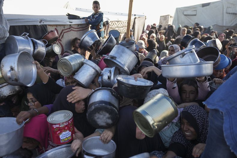ARCHIVO - Mujeres y niñas palestinas tratan de conseguir comida en un centro de distribución de Jan Yunis, en la Franja de Gaza, el viernes 6 de diciembre de 2024. (AP Foto/Abdel Kareem Hana, Archivo)