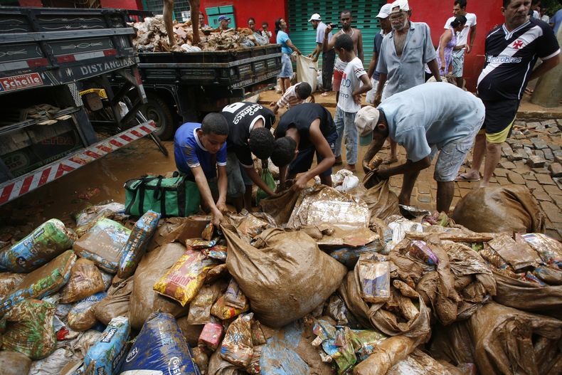 Varias personas recolectan alimentos empapados de lodo y lluvia afuera de un supermercado en la municipalidad de Itaguacu, estado Espirito Santo, Brasil, el mi&eacute;rcoles 25 de diciembre de 2013. (Foto AP/Vitor Jubino-A Gazeta)