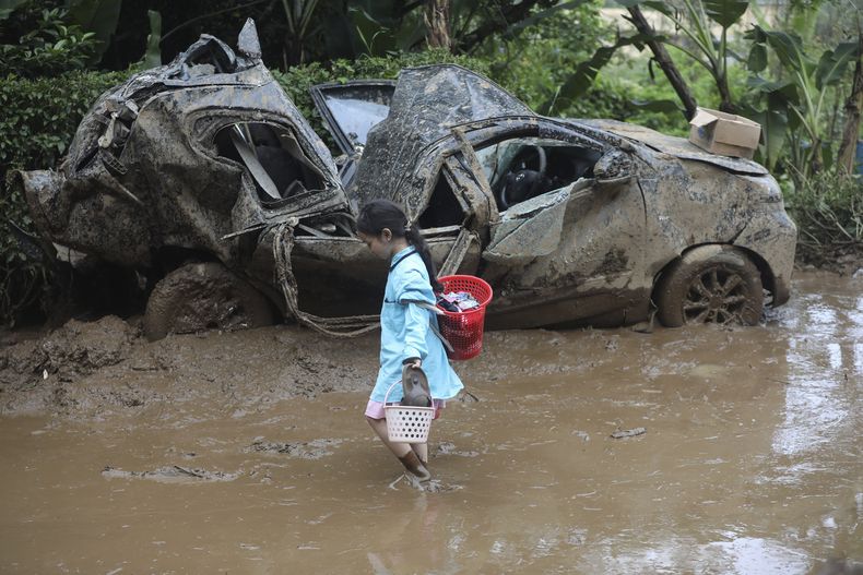 Una niña camina cerca de un vehículo aplastado por un deslave, en Karo, Indonesia, el 25 de noviembre de 2024. (AP Foto/Binsar Bakkara)