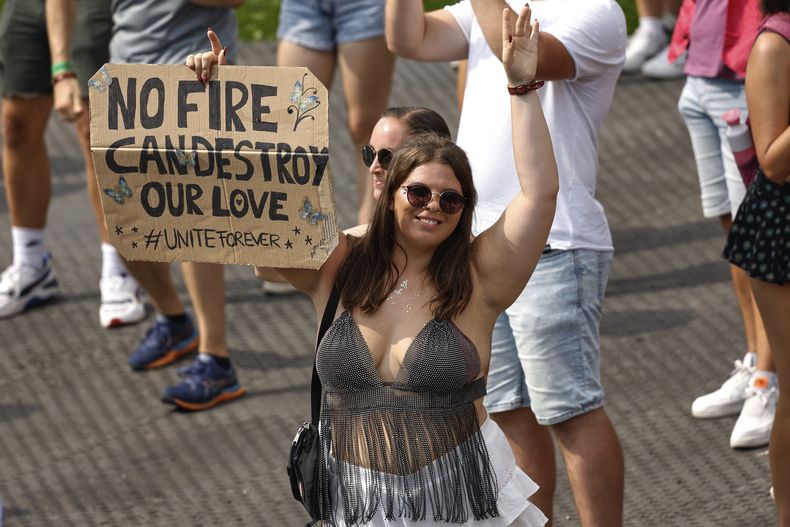 Una mujer sostiene un cartel mientras Odymel y Pegassi actúan en el festival de música Tomorrowland en Boom, Bélgica, el viernes 18 de julio de 2025, dos días después de que un gran incendio el miércoles dañara gravemente el escenario principal. (Foto AP/Omar Havana)