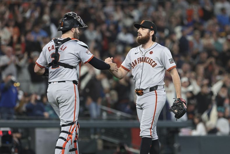 El receptor de los Gigantes de San Francisco, Curt Casali, a la izquierda, y el lanzador Ryan Walker celebran después de derrotar a los Marineros de Seattle 4-3 el sábado 24 de agosto de 2024, en Seattle. (AP Foto/Jason Redmond)
