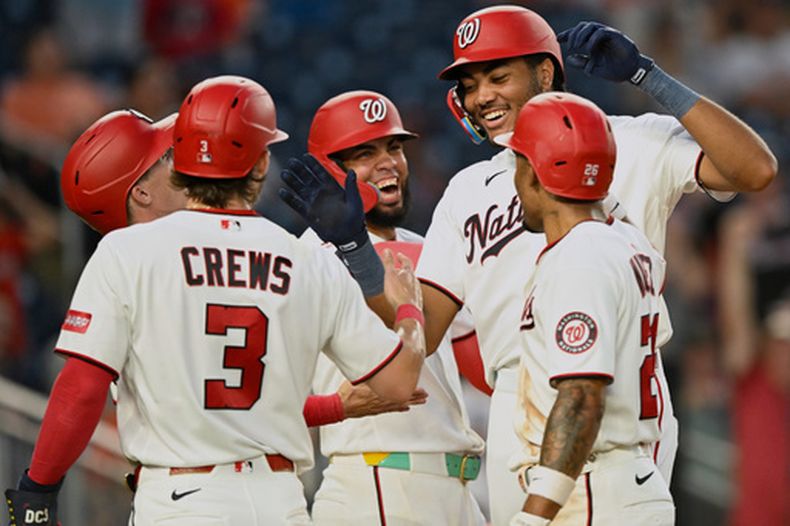 James Wood, de los Nacionales de Washington, es felicitado en el plato por sus compañeros de equipo después de batear un grand slam durante la quinta entrada del juego de béisbol de Grandes Ligas contra los Astros de Houston, el lunes 6 de julio de 2026, en Washington. (AP Foto/John McDonnell)