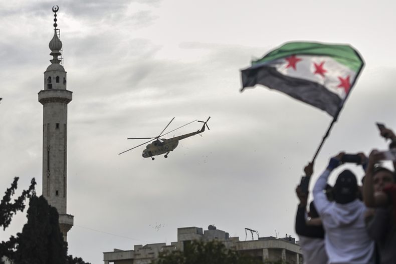 Un helicóptero militar arroja confeti y flores sobre la multitud durante la celebración del 10mo aniversario de la victoria de las fuerzas rebeldes sobre el ejército del expresidente Bashar al-Assad en Idlib, Siria, el 28 de marzo de 2025. (AP Foto/Ghaith Alsayed)