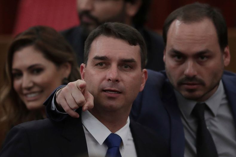 ARCHIVO - Flavio Bosonaro, en el centro, y Carlos Bolsonaro, hijos del presidente electo de Brasil, Jair Bolsonaro, asisten a una ceremonia en el Supremo Tribunal Electoral de Brasilia, Brasil, el 10 de diciembre de 2018, en la que se confirmaron oficialmente los resultados de las elecciones presidenciales que ganó su papá. (AP Foto /Eraldo Peres/Archivo)