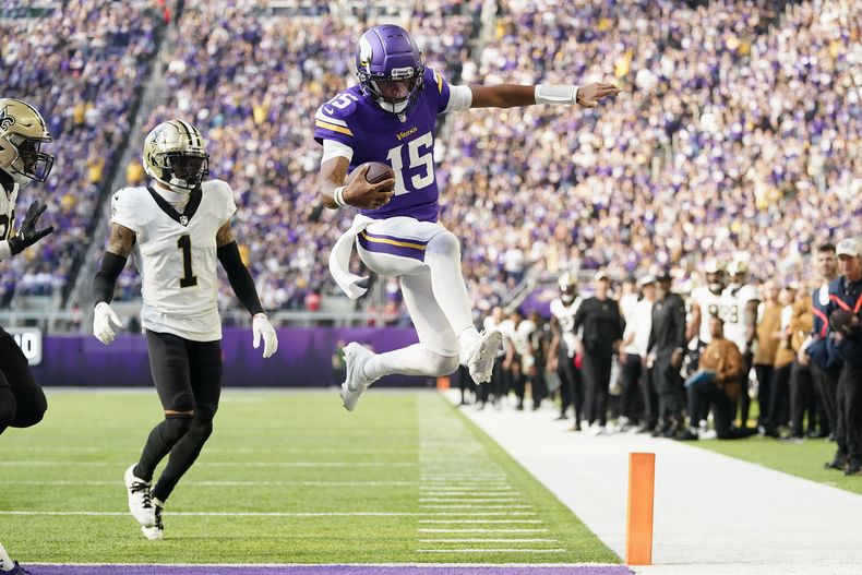El quarterback de los Vikings de Minnesota Joshua Dobbs (15) corre para un touchdown frente al cornerback de los Saints de Nueva Orleans Alontae Taylor (1) durante la primera mitad del juego de NFL el domingo 12 de noviembre de 2023, en Mineápolis. (AP Foto/Abbie Parr)
