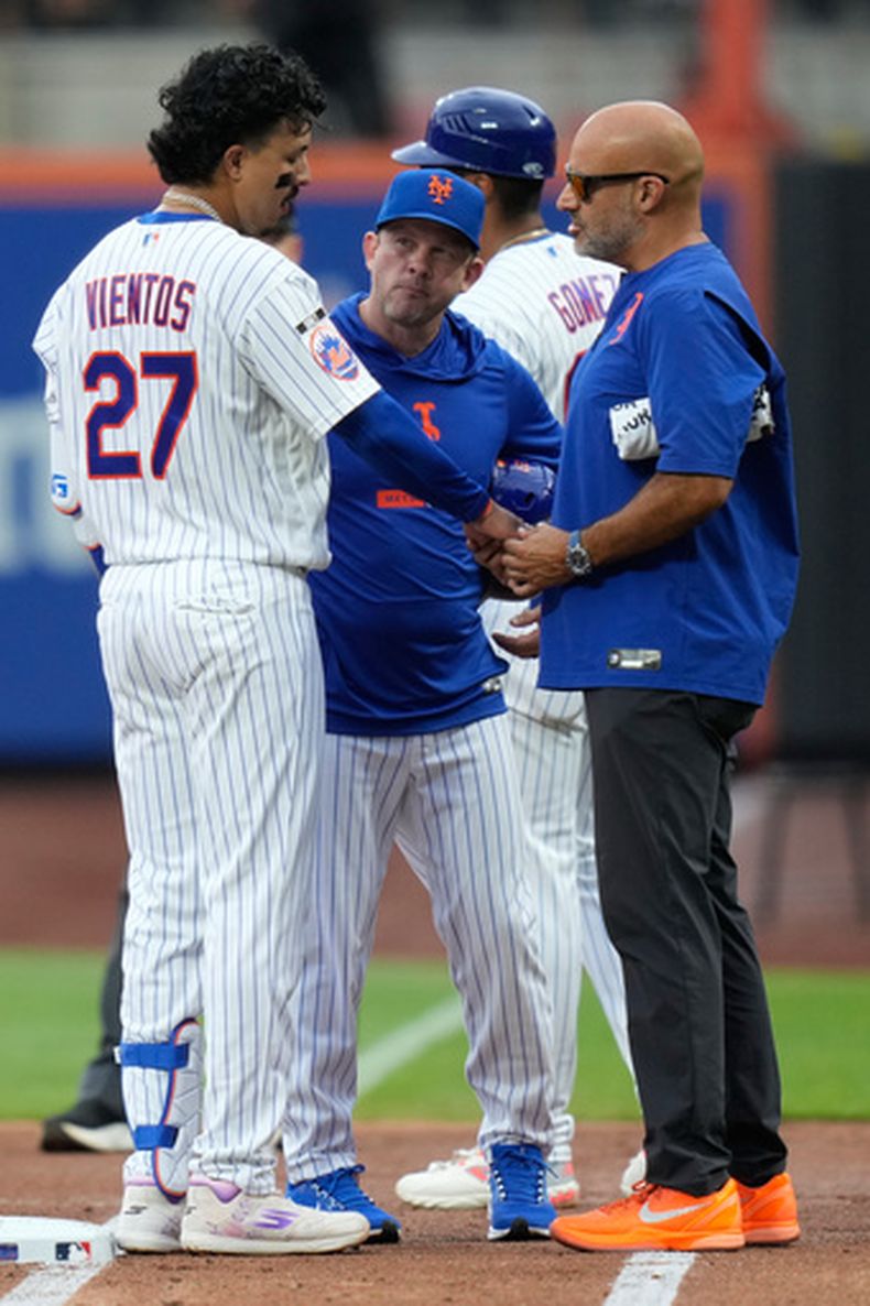 Andy Green, centro, mánager interino de los Mets de Nueva York, observa a Mark Vientos, izquierda, mientras es revisado por el personal médico del equipo después de haber sido golpeado en la segunda entrada del juego de béisbol de Grandes Ligas contra los Reales de Kansas City, el jueves 9 de julio de 2026, en Nueva York. (AP Foto/Seth Wenig)