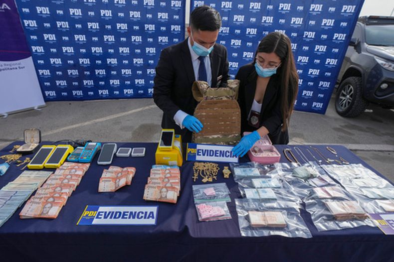 Miembros de la Policía de Investigaciones (PDI) exhiben objetos incautados durante la Operación Tokio para una conferencia de prensa en Santiago de Chile, el martes 2 de junio de 2026. Según la PDI, la operación desmanteló una célula local de la organización criminal Tren de Aragua. (Foto AP/Esteban Félix)