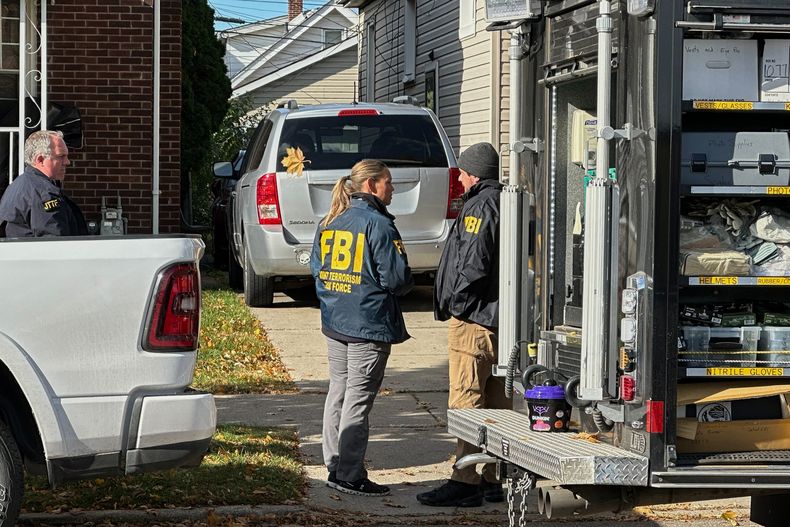 Agentes del FBI se reúnen frente a una casa en un vecindario de Dearborn, Michigan, el viernes 31 de octubre de 2025. (Foto AP/Mike Householder)