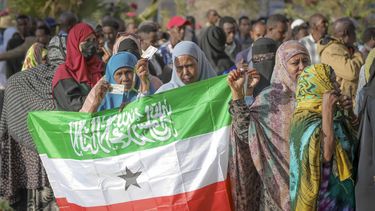 Una mujer muestra la bandera de Somalilandia mientras la gente espera a votar en las elecciones presidenciales de 2024 en un centro electoral en Hargeisa, Somalilandia, el miércoles 13 de noviembre de 2024. (AP Foto/Abdirahman Aleeli)