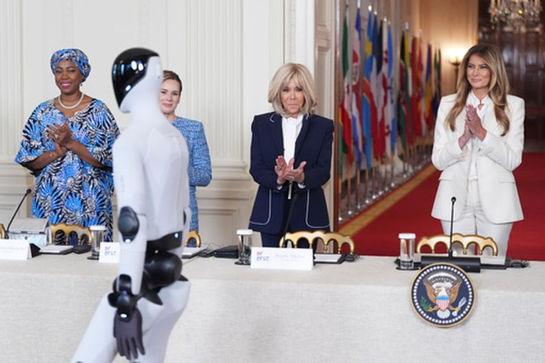 La primera dama de Estados Unidos, Melania Trump, llega acompañada de un robot, a la Cumbre de la Coalición Global Fostering the Future Together (“Promover juntos el futuro”) con otras primeras damas, en la Casa Blanca, el miércoles 25 de marzo de 2026. en Washington. De izquierda a derecha, la doctora Fatima Maada Bio, de Sierra Leona, Martha Nawrocka de Polonia, Brigitte Macron de Francia, y Melania Trump. (AP Foto/Jacquelyn Martin)