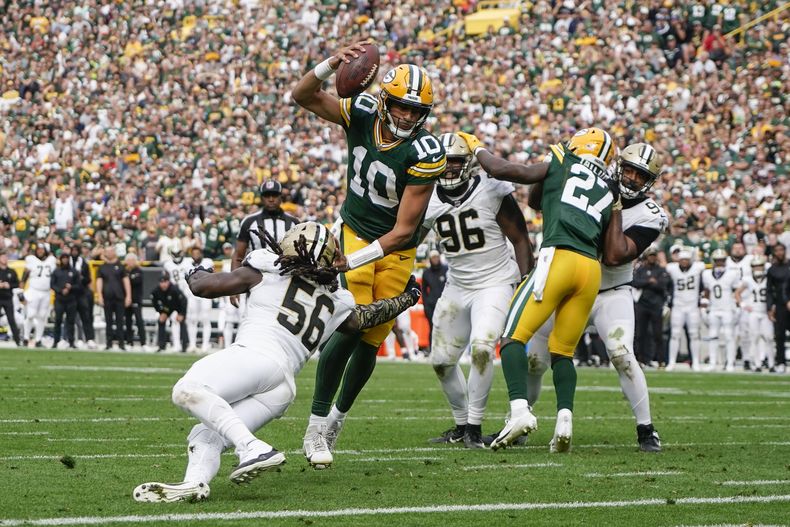Jordan Love (10), quarterback de los Packers de Green Bay, esquiva una tackleada del linebacker de los Saints de Nueva Orleans, Demario Davis (56), en una jugada que terminó en acarreo de touchdown en la segunda mitad del juego de la NFL, el domingo 24 de septiembre de 2023, en Green Bay, Wisconsin. (AP Foto/Morry Gash)