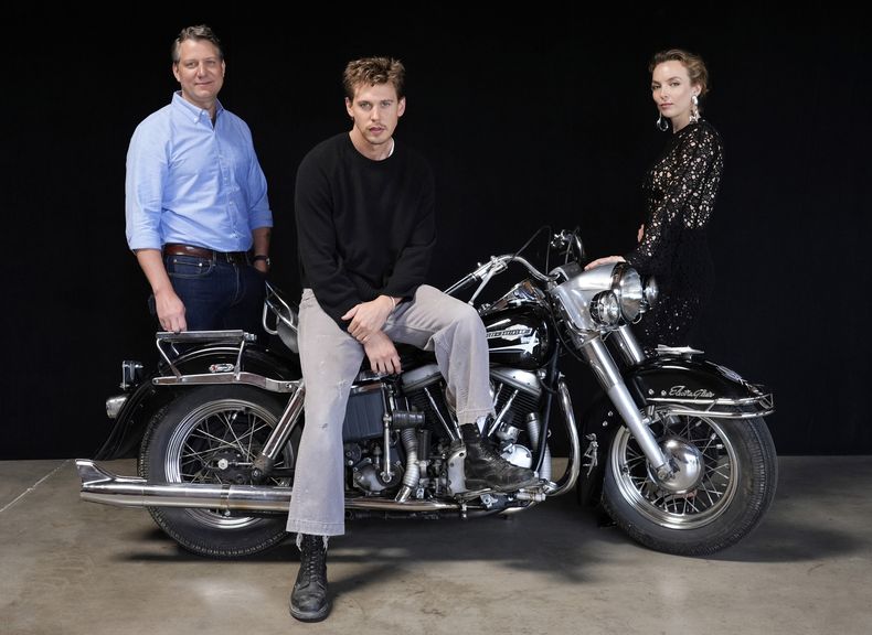 Jeff Nichols, izquierda, guionista y director de The Bikeriders posa con los miembros del elenco Austin Butler, centro, y Jodie Comer, el jueves 30 de mayo de 2024 en Los Angeles. La motocicleta es una Harley Davidson Pan Head 1965 que Butler montó en la película. (Foto AP/Chris Pizzello)