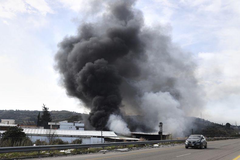 Humo sale de una fábrica que sufrió un ataque durante los enfrentamientos entre fuerzas de seguridad sirias y grupos armados leales al expresidente Bashar Assad en las afueras de Latakia, Siria, el viernes 7 de marzo de 2025. (AP Foto/Omar Albam)
