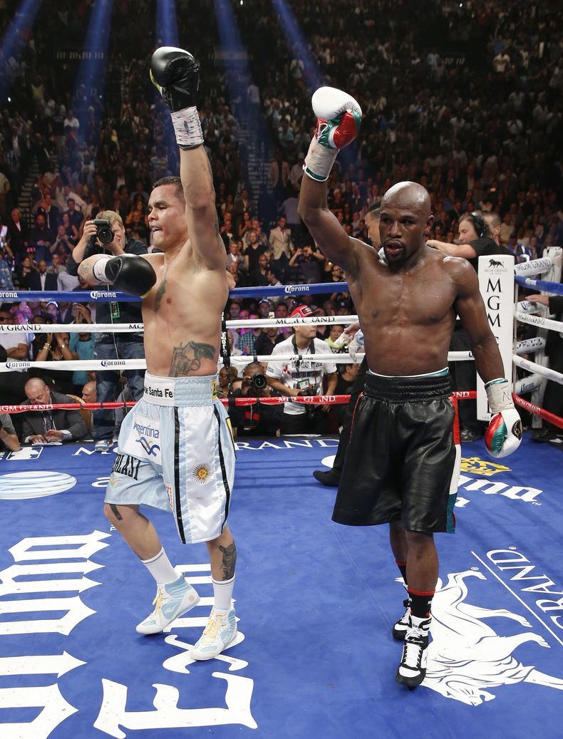El estadounidense Floyd Mayweather Jr., a la derecha, y el argentino Marcos Maidana, alzan los brazos en se&ntilde;al de victoria al cabo de su pelea por el t&iacute;tulo welter del Consejo Mundial de Boxeo y la Asociaci&oacute;n Mundial de Boxeo en Las V