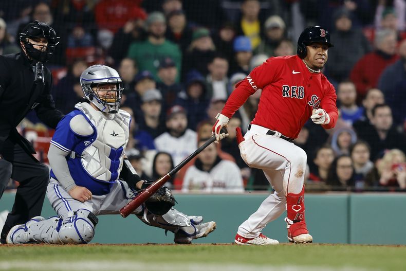 El dominicano Enmanuel Valdez, de los Medias Rojas de Boston, conecta un sencillo de dos carreras, adelante del cátcher mexicano Alejandro Kirk, de los Azulejos de Toronto, el miércoles 3 de mayo de 2023 (AP Foto/Michael Dwyer)