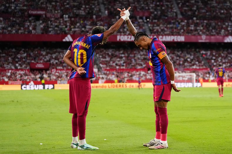Raphinha celebra con su compañero del Barcelona Lamine Yamal tras anotar el segundo gol de su equipo en el encuentro de La Liga ante el Sevilla el sábado 19 de septiembre del 2026. (AP Foto/Jose Breton)
