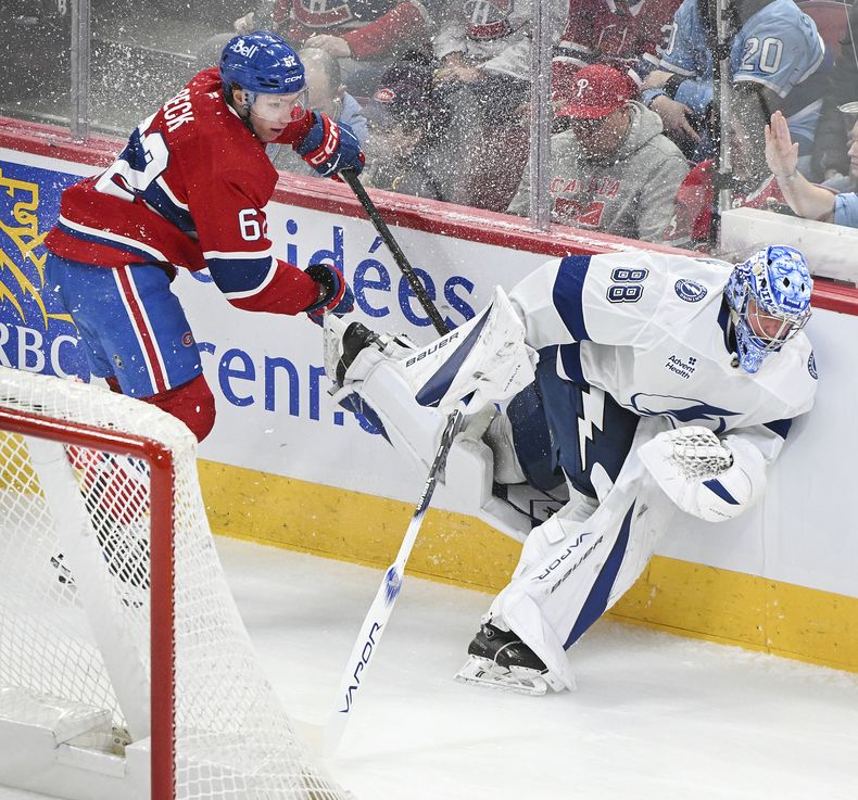 Owen Beck, de los Canadiens de Montreal, atora su bastón con Andrei Vasilevskiy, portero del Lightning de Tampa Bay, en un partido del domingo 9 de febrero de 2025 (Graham Hughes/The Canadian Press via AP)