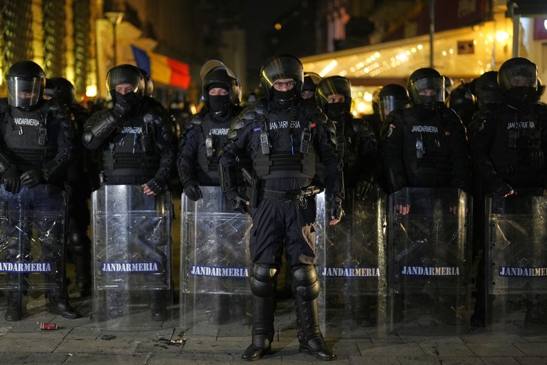 Policías forman una barrera frente a simpatizantes de Calin Georgescu, quienes realizaban una protesta después de que el organismo electoral de Rumania rechazó su candidatura en la elección presidencial, el domingo 9 de marzo de 2025, en Bucarest, Rumania. (AP Foto/Vadim Ghirda)