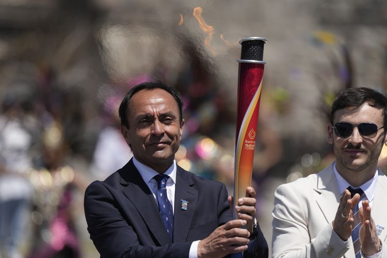 El ministro de Deportes de Chile, Jaime Pizarro, a la izquierda, y el deportista chileno Tomás González, posan con la antorcha durante el encendido de la llama panamericana, en el sitio arqueológico de Teotihuacan, el viernes 29 de septiembre de 2023, en México. (AP Foto/Fernando Llano)