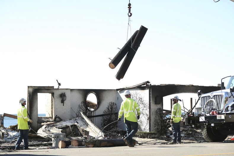 Trabajadores de Southern California Edison retiran un poste de energía carbonizado después del incendio Palisades en Malibú, California, el domingo 12 de enero de 2025. (Scott Strazzante/San Francisco Chronicle via AP)