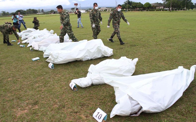 Soldados colombianos caminan junto bolsas con cad&aacute;veres de 10 rebeldes muertos en combates con soldados del ej&eacute;rcito, de acuerdo con las autoridades,  en una base militar en Tame, en el departamento de Arauca, Colombia, el domingo 24 de novi