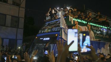 Imane Khelif, campeona olímpica de boxeo, saluda a la multitud desde un autobús, al desfilar por Tiaret, Argelia, el viernes 16 de agosto de 2024 (AP Foto/Anis Belghoul)