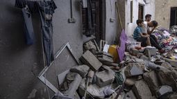 Palestinos sentados entre los escombros de una casa después de que fuera alcanzada por un bombardeo israelí en Khan Younis, en el sur de la Franja de Gaza, el domingo 29 de octubre de 2023. (AP Foto/Fatima Shbair)