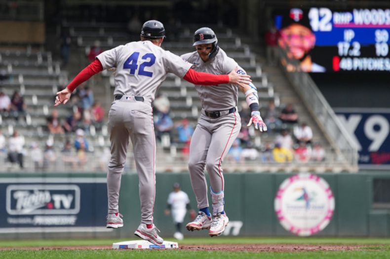 Trevor Story, derecha, de los Medias Rojas de Boston, celebra con el coach de tercera base Kyle Hudson después de batear jonrón de tres carreras durante la tercera entrada del juego de béisbol de Grandes Ligas ante los Mellizos de Minnesota el miércoles 15 de abril de 2026, en Minneapolis. (AP Foto/Abbie Parr)