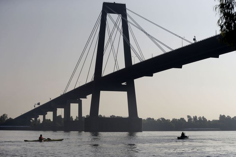 ARCHIVO - Dos personas pasan en canoa bajo el puente Hale Boggs en el río Mississippi en Luling, Luisiana, el 25 de julio de 2014. (AP Foto/Gerald Herbert, Archivo)