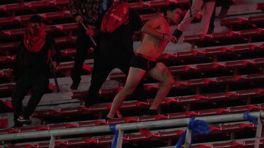 Hinchas del club argentino Independiente agreden a un fanático de la Universidad de Chile (derecha) tras sacarle la ropa durante el partido por los octavos de final de la Copa Sudamericana, el miércoles 20 de agosto de 2025, en Avellaneda, Argentina. (AP Foto/Gustavo Garello)