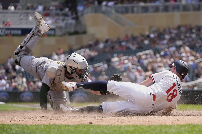 Kody Clemens (18) de los Mellizos de Minnesota es puesto out con un toque del receptor de los Atléticos, Willie MacIver (65), para terminar la parte baja de la cuarta entrada de un juego de béisbol el jueves 21 de agosto de 2025, en Mineápolis. (AP Photo/Abbie Parr)