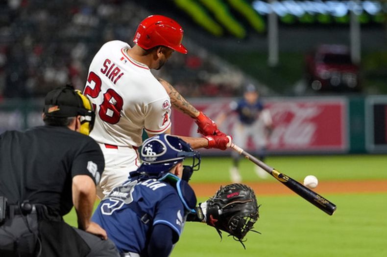 José Siri (28), de los Angelinos de Los Ángeles, batea un jonrón de dos carreras mientras Hunter Feduccia, de los Rays de Tampa Bay, y el umpire principal Dave Rackley observan durante la séptima entrada del juego de béisbol de Grandes Ligas, el sábado 13 de junio de 2026, en Anaheim, California. (AP Foto/Mark J. Terrill)