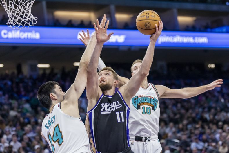 El pívot de los Kings de Sacramento Domantas Sabonis salta para tirar el balón de bandeja frente al pívot de los Grizzlies de Memphis Zach dey en el encuentro del lunes 17 de marzo del 2025. (AP Foto/Sara Nevis)
