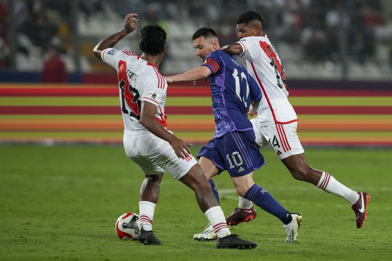 Lionel Messi, de la selección de Argentina, avanza entre Renato Tapia (izquierda) y Wilder Cartagena, de Perú, en un encuentro de la eliminatoria mundialista, el martes 17 de octubre de 2023, en Lima (AP Foto/Guadalupe Pardo)