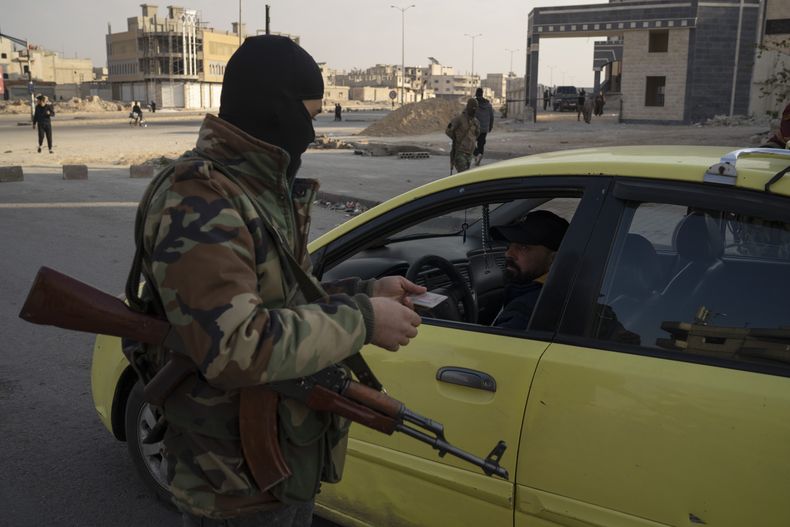 Un miembro de la policía del recién formado gobierno sirio verifica la identificación de un conductor en un control de seguridad en Homs, Siria, el jueves 26 de diciembre de 2024. (Foto AP/Leo Correa)