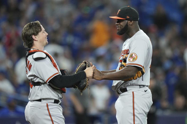 El receptor Adley Rutschman (izquierda) y el relevista Félix Bautista celebran tras la victoria ante los Azulejos de Toronto, el lunes 31 de julio de 2023, en Toronto. (Nathan Denette/The Canadian Press vía AP)