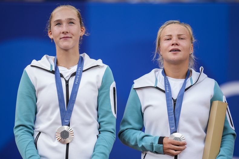Las atletas neutrales Mirra Andreeva y Diana Shnaider muestran sus medallas de platas tras perder ante las italianas Sara Errani y Jasmine Paolini en la final del dobles femenino de los Juegos Olímpicos de París, el domingo 4 de agosto de 2024.. (AP Foto/Manu Fernändez)