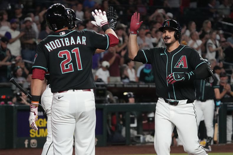 Nolan Arenado, derecha, de los Diamondbacks de Arizona, celebra con Tyler Locklear y Lars Nootbaar (21) después de batear un grand slam contra los Rockies de Colorado en la segunda entrada del juego de béisbol de Grandes Ligas, el lunes 10 de agosto de 2026, en Phoenix. (AP Foto/Rick Scuteri)