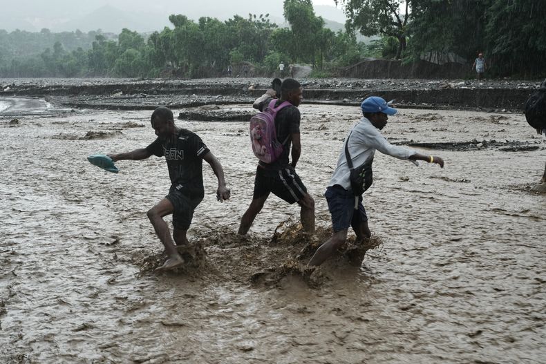 Los residentes vadean un arroyo inundado tras el huracán Melissa en Petit-Goave, Haití, el jueves 30 de octubre de 2025. (AP Foto/Odelyn Joseph)