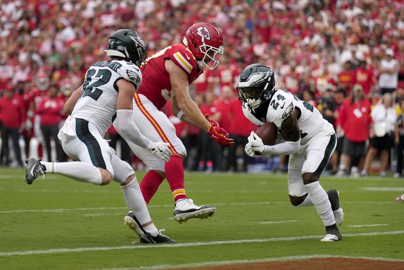 Andrew Mukuba (24), safety de los Eagles de Filadelfia, intercepta un pase que le pegó en las manos a Travis Kelce, centro, ala cerrada de los Chiefs de Kansas City, mientras Reed Blankenship (32), de los Eagles, observa la acción durante la segunda mitad del partido de la NFL, el domingo 14 de septiembre de 2025, en Kansas City, Missouri. (AP Foto/Charlie Riedel)