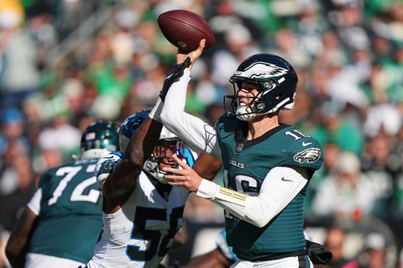 El quarterback de los Eagles de Filadelfia Tanner McKee intenta lanzar el balón bajo presión del linebacker de los Panthers de Carolina Bobby Okereke en el encuentro del domingo 18 de octubre del 2026. (AP Foto/Matt Rourke)