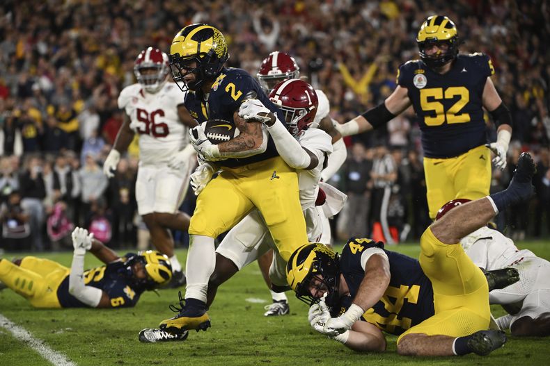 Blake Corum (2), running back de Michigan, corre para un touchdown superando a Kool-Aid McKinstry (1), defensive back de Alabama, durante el tiempo extra del Rose Bowl, semifinal de la NCAA del fútbol americano colegial, el lunes 1 de enero de 2024, en Pasadena, California. (AP Foto/Kyusung Gong)
