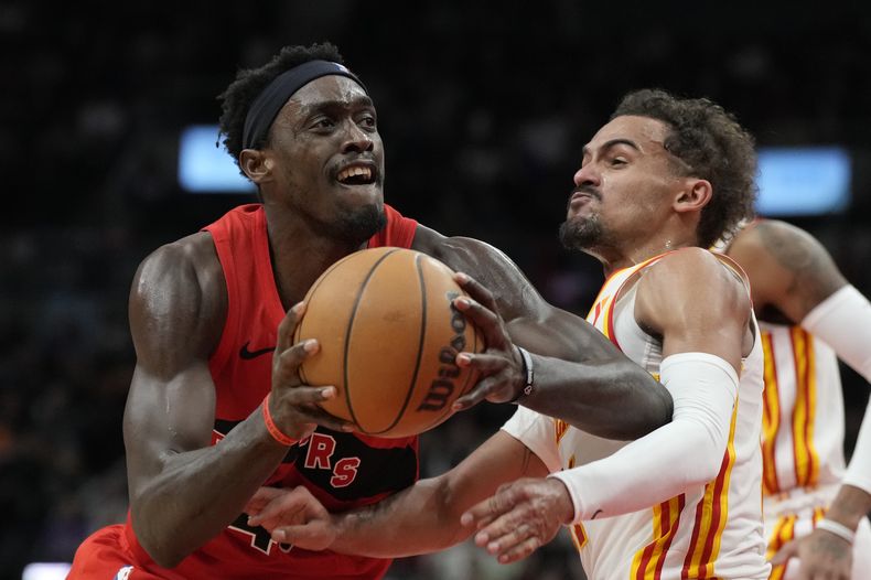 Pascal Siakam, alero de los Raptors de Toronto, controla el balón frente a Trae Young, base de los Hawks de Atlanta, en el encuentro del miércoles 13 de diciembre de 2023 (Frank Gunn/The Canadian Press via AP)