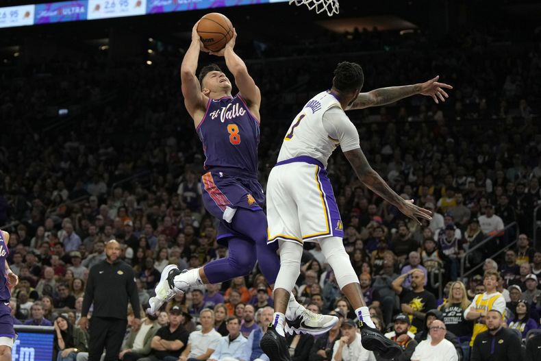 El base de los Suns de Phoenix Grayson Allen salta con el balón hacia la canasta frente al base de los Lakers de Los Ángeles DAngelo Russell en el encuentro de la NBA del domingo 25 de febrero del 2024. (AP Foto/Rick Scuteri)