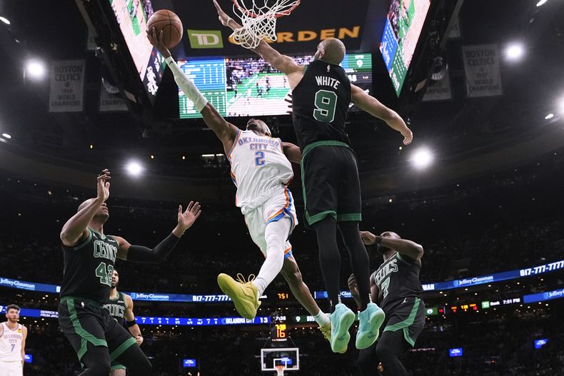 El base del Thunder de Oklahoma City Shai Gilgeous-Alexander avanza hacia la canasta frente al base de los Celtics de Boston Derrick White en el encuentro del miércoles 12 de marzo del 2025. (AP Foto/Charles Krupa)