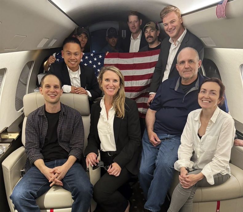 Esta imagen distribuida por la Casa Blanca muestra a Evan Gershkovich, izquierda, Alsu Kurmasheva, derecha, y Paul Whelan, segundo de la derecha, junto con otras personas a bordo de un avión el 1 de agosto de 2024 tras un intercambio de prisioneros con Rusia. (Casa Blanca vía AP)